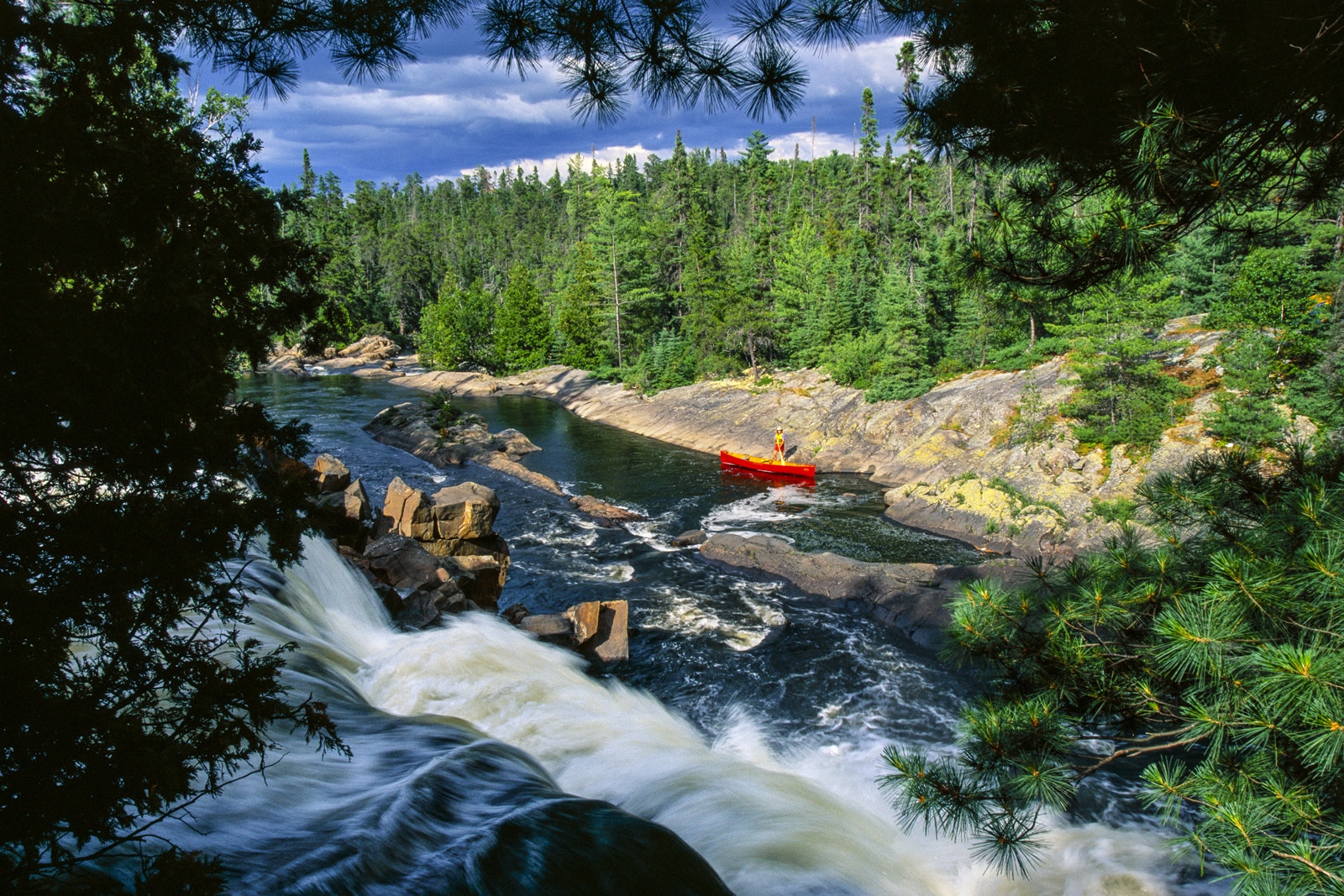 Canoer on shore of river with rapids