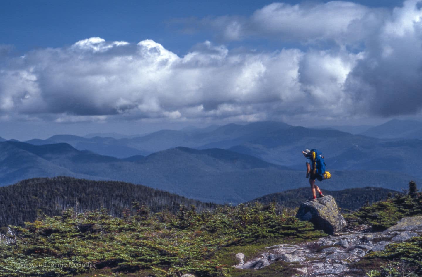 Hiker standing on a rock looking out on the mountains 