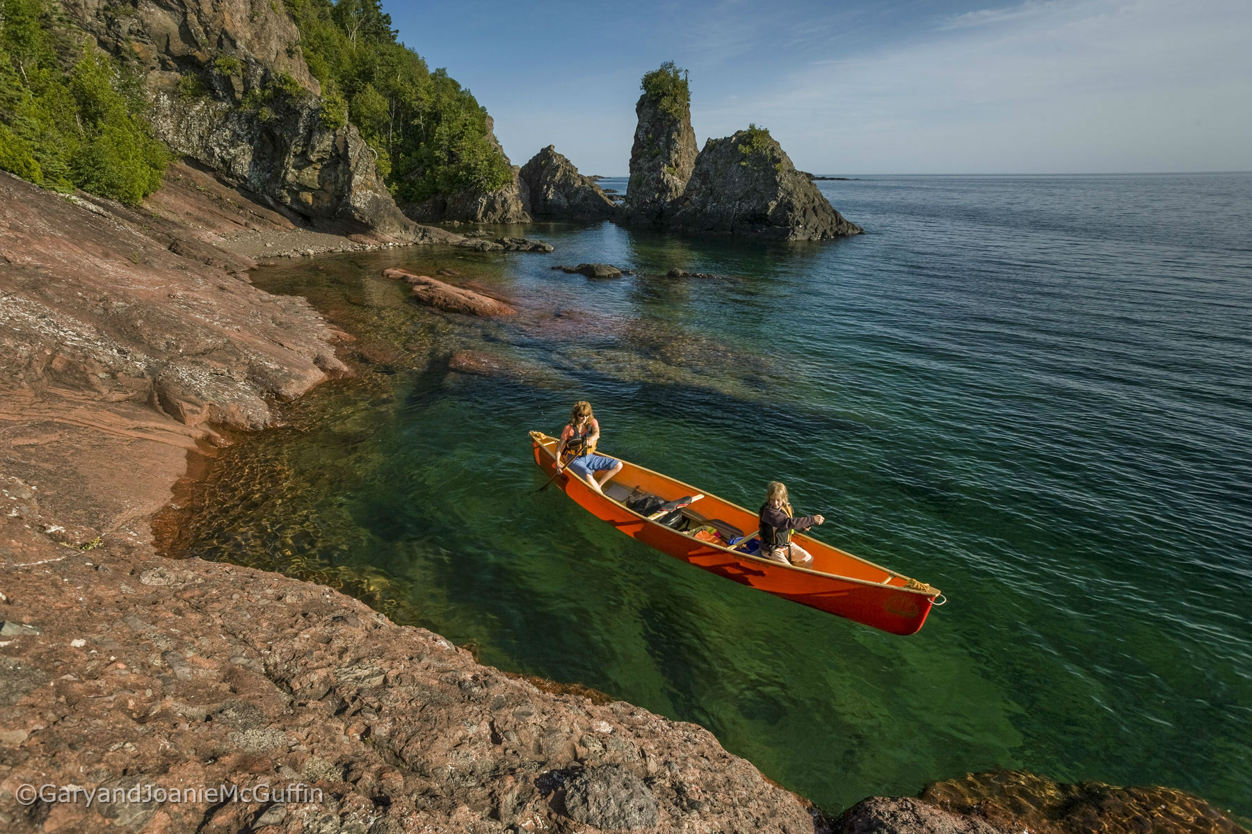 Two paddlers canoeing along shore line